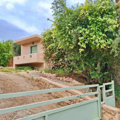a house with a fence in front of a tree at The Leaf House in Varípetron