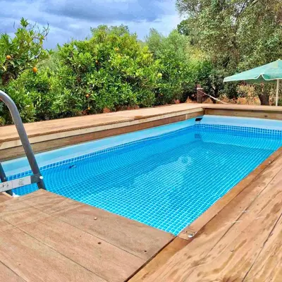 an empty swimming pool with a wooden deck and an umbrella at The Leaf House in Varípetron
