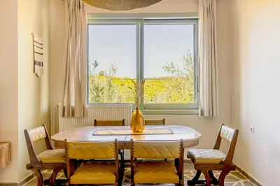 a dining room with a table and chairs and a window at The Leaf House in Varípetron