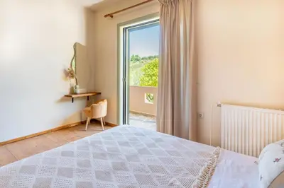 a bedroom with a bed and a sliding glass door at The Leaf House in Varípetron