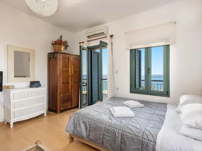 a bedroom with a bed and a dresser and windows at The Hillside Home in Plataniás