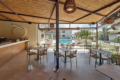 a restaurant with tables and chairs and a pool at Inea Sole Boutique Hotel in Kato Daratso