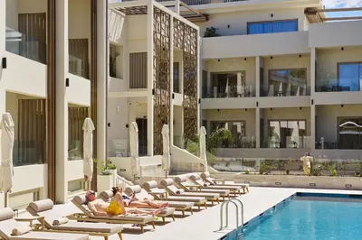 a group of people sitting on lounge chairs next to a swimming pool at Inea Sole Boutique Hotel in Kato Daratso