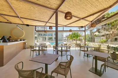 a restaurant with tables and chairs and a pool at Inea Sole Boutique Hotel in Kato Daratso