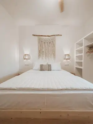 a white bedroom with a large white bed with two lights at Stella's Boho Retreat in Palaiochóra