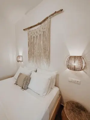 a bedroom with a bed with white sheets and two lights at Stella's Boho Retreat in Palaiochóra
