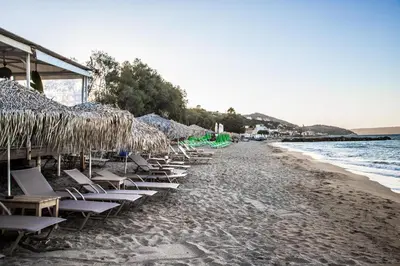 a row of chairs and straw umbrellas on a beach at Kalyves Pearl apartments by the sea in Kalyves