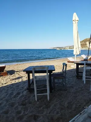 a table and chairs and an umbrella on the beach at Kalyves Pearl apartments by the sea in Kalyves