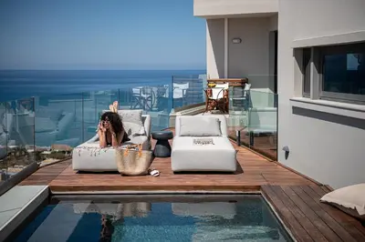 a woman laying on a couch next to a swimming pool at Alectrona Living Crete, Apartment Olīvea in Plataniás