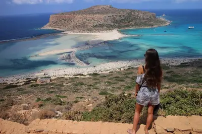 a woman standing on top of a cliff looking at the ocean at Horizonte Seafront Suites in Kissamos