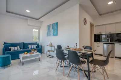 a living room with a blue couch and a table and chairs at Lysithea Apartments - brand new, stylish & central in Kissamos