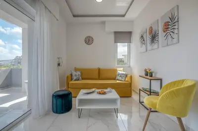 a living room with a yellow couch and a table at Lysithea Apartments - brand new, stylish & central in Kissamos