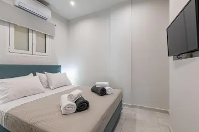 a bedroom with a bed with towels and a flat screen tv at Neaira City Apartment Near The Beach in Chania Town
