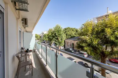 a balcony with a table and chairs and a street at Neaira City Apartment Near The Beach in Chania Town