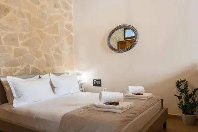 a bedroom with a white bed with a mirror on the wall at Pleiades Apartments in Chania Town