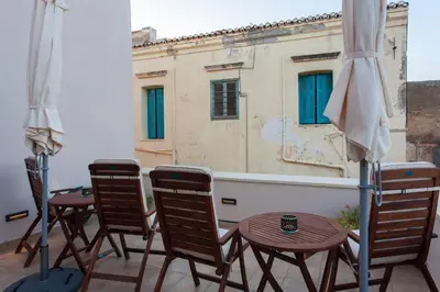 a balcony with chairs and tables and a building at Pleiades Apartments in Chania Town
