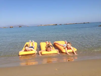 three children laying on rafts in the water on the beach at Candia Hotel in Chania Town