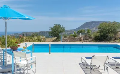 a pool with a table and chairs and an umbrella at Villa Lefki in Vamos