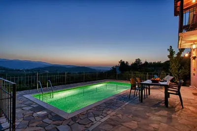 a pool with a table and chairs next to a house at Citrea Villa in Fournés