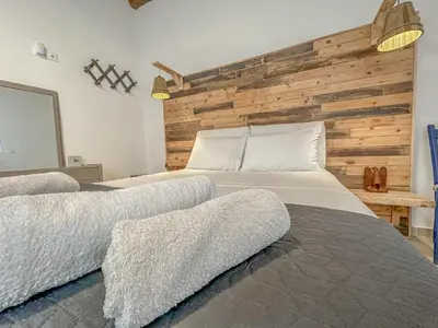 a bedroom with two beds and a wooden wall at Mountain Bliss Guesthouse 1 next to Sougia in Agrilés