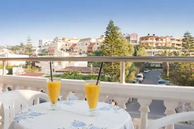 two glasses of orange juice sitting on a table on a balcony at Papidakis Studios in Agia Marina Nea Kydonias