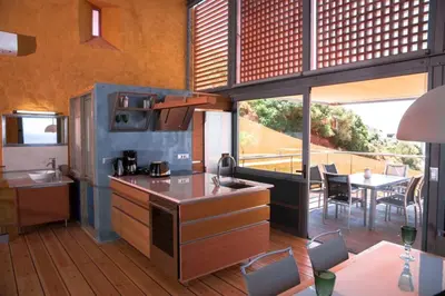 a kitchen with a counter and a table with chairs at Seafront Ravdoucha Epavlis Athina Villa - Pool, Gym, Sauna, Private Parking, WiFi in Ravdhoúkha