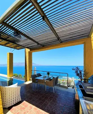 a patio with a table and a view of the ocean at Beachfront Ravdoucha Epavlis Eleni Villa - Pool, Hot Tub, Gym, Sauna, Private Parking, WiFi in Chania Town