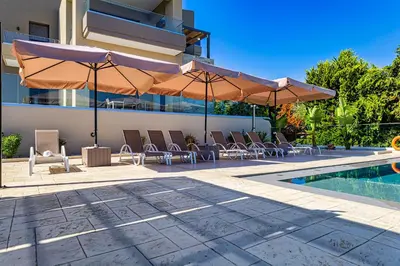 a pool with chairs and umbrellas next to a building at Chris villa with private ecologic pool and kid's playground! in Chania Town