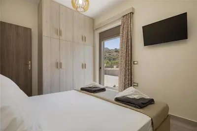 a bedroom with a bed with a television and a window at Chris villa with private ecologic pool and kid's playground! in Chania Town