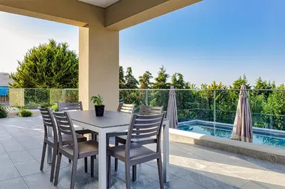 a table and chairs on a patio with a pool at Chris villa with private ecologic pool and kid's playground! in Chania Town