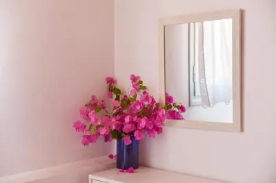 a vase with pink flowers sitting on a table in front of a mirror at Seasound apartments in Galatás