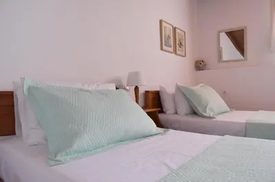 a bedroom with two beds with green and white pillows at Seasound apartments in Galatás