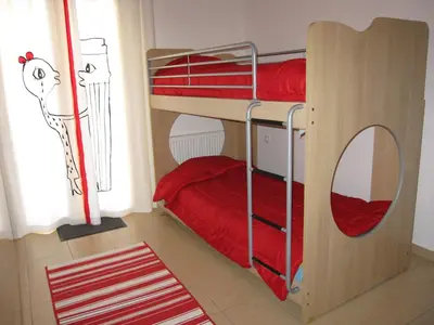 a bedroom with bunk beds with red sheets and a window at Villa Pandora - Angela & Michali in Maleme