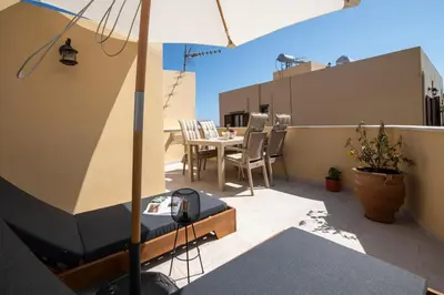 a balcony with a table and chairs and an umbrella at DELUXE MAISONETTE in Chania Town