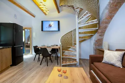 a living room with a spiral staircase and a table at DELUXE MAISONETTE in Chania Town