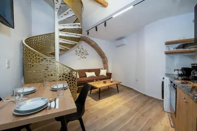 a living room with a table and a spiral staircase at DELUXE MAISONETTE in Chania Town