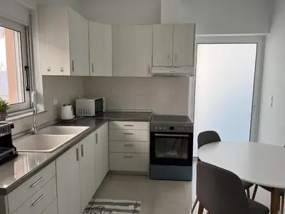 a kitchen with white cabinets and a table and a sink at Veryhome in Maleme