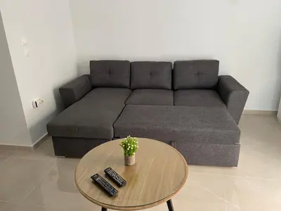 a living room with a couch and a table with remotes at Veryhome in Maleme