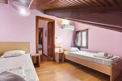 two beds in a room with pink walls and wooden floors at Emmanouel Maisonette near the Sea in Parigoría