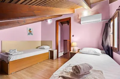 two beds in a room with pink walls and wooden floors at Emmanouel Maisonette near the Sea in Parigoría