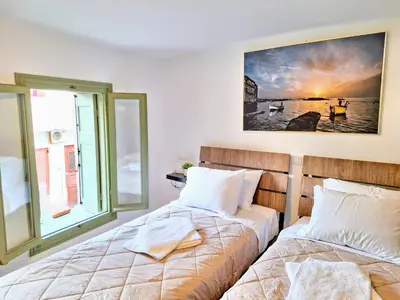 two beds in a room with a window at Icarus Loft Old Town rooftop terrace in Chania Town