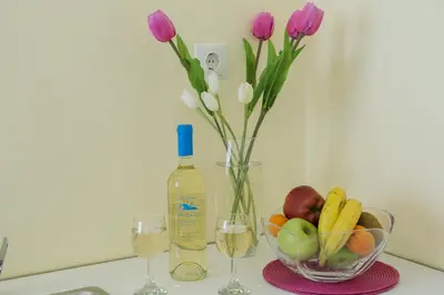 a bottle of wine and a vase with flowers and fruit at Penelopi Rooms in Chania Town