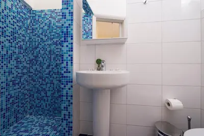 a bathroom with a sink and a shower with blue tiles at Penelopi Rooms in Chania Town