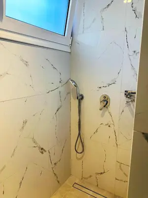 a shower in a bathroom with white marble walls at Matina Room in Chania Town