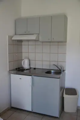 a small kitchen with white cabinets and a sink at Hotel Stavris in Khóra Sfakíon