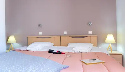 a bed with a bottle of wine and a book on it at Anchris Paleochora in Palaiochóra