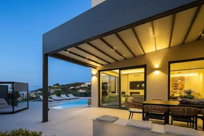 a house with a patio with a table and chairs at Kalyves Royal Villa I 