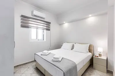 a white bedroom with a bed and a window at Villa Athena by Villa Plus in Almirida