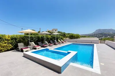 a pool with chairs and umbrellas on a house at Villa Athena by Villa Plus in Almirida