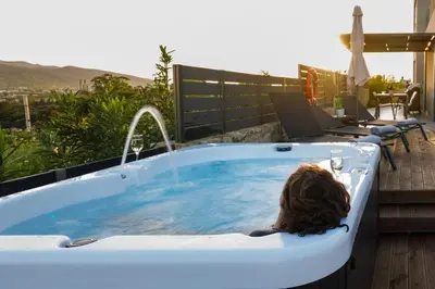 a woman is sitting in a bath tub with water at Thearia villa I - seaview , private heated pool & jacuzzi in Souda